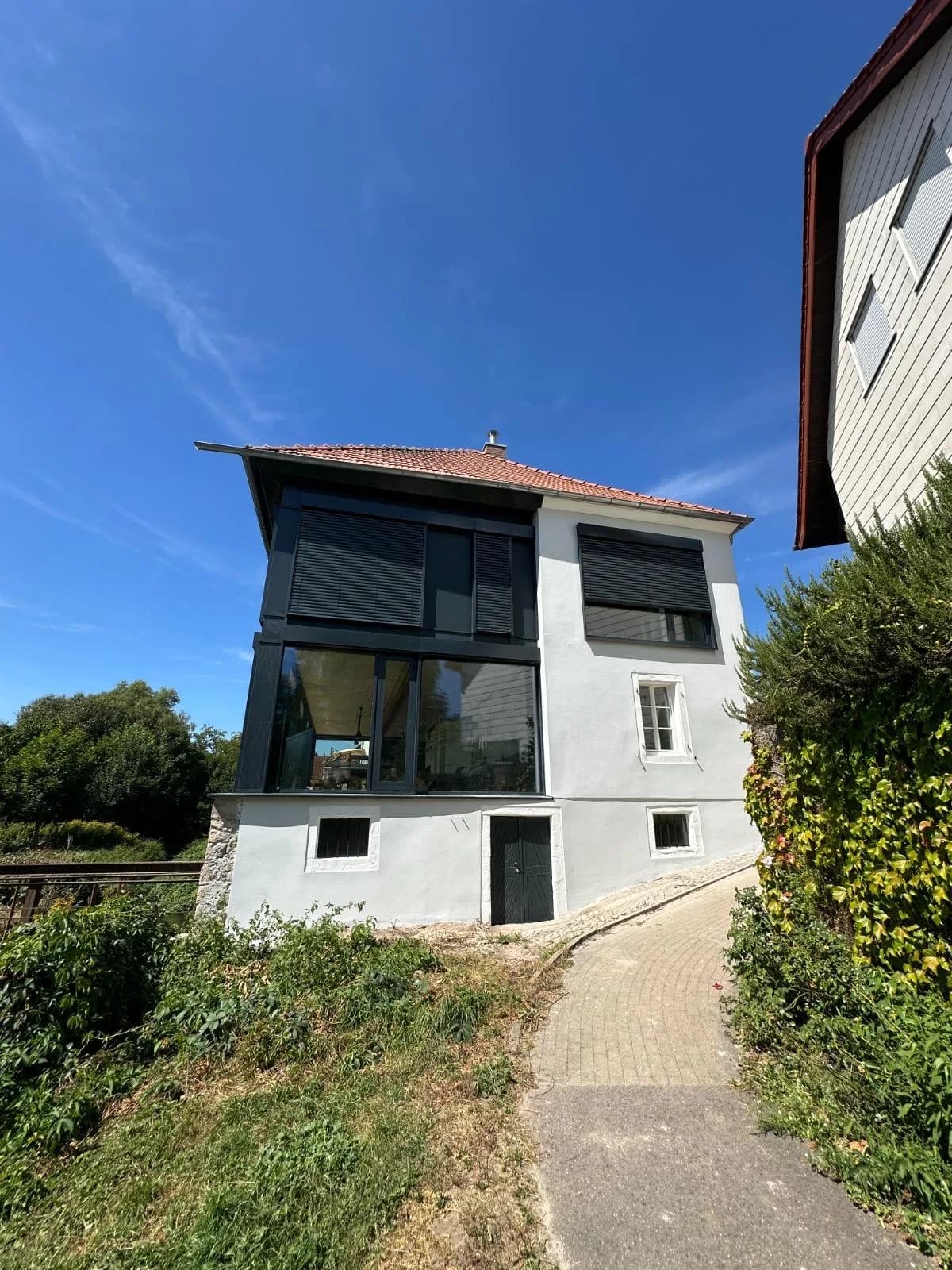Sanierter Altbau mit grossflaechigem Panorama-Fenster und anthrazitfarbenen Raffstoren an der Fassade — Referenzprojekt Fenstertausch Labisch, Saarland