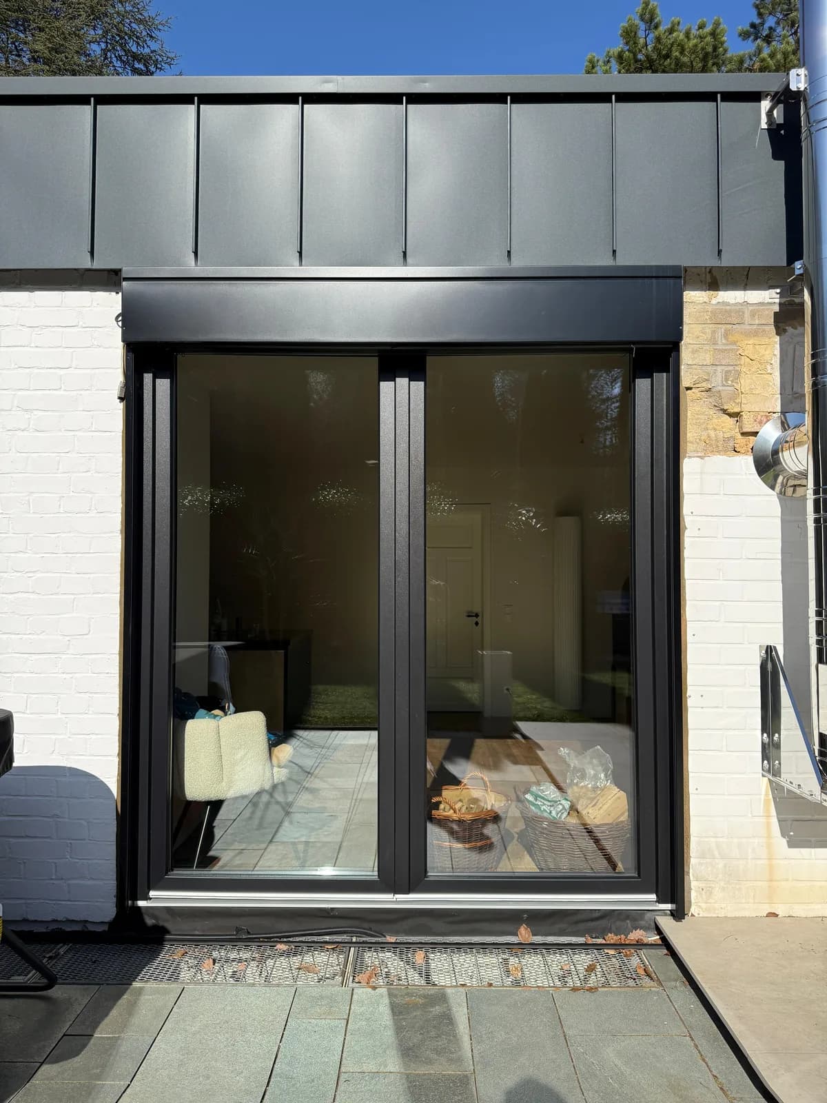 Massives anthrazitfarbenes Aluminium-Schiebeelement in einem modernen Anbau mit Zinkblech-Verkleidung und Naturstein-Sockel — Referenzprojekt Fenster Labisch, Saarland