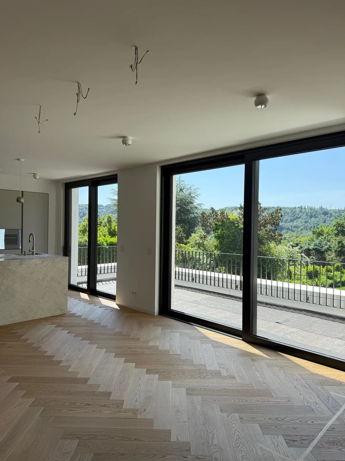 Grossformatige Hebe-Schiebetuer im Wohnbereich mit heller Marmor-Kochinsel und Blick auf die Terrasse — Referenzprojekt Fenster Labisch, Saarpfalz